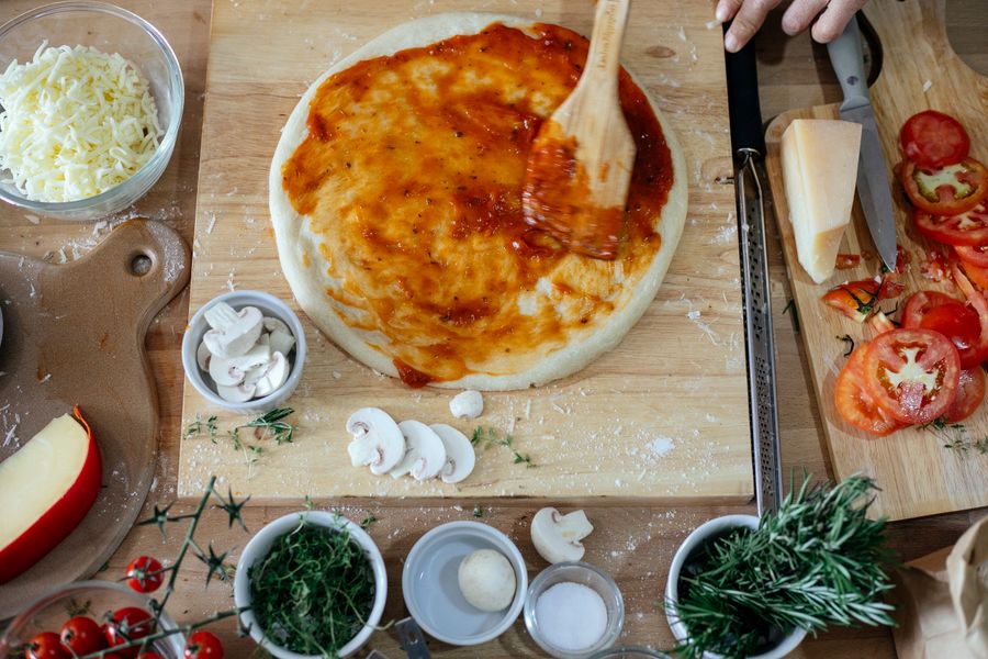 Manos de maestro pizzaiolo preparando la masa con ingredientes frescos