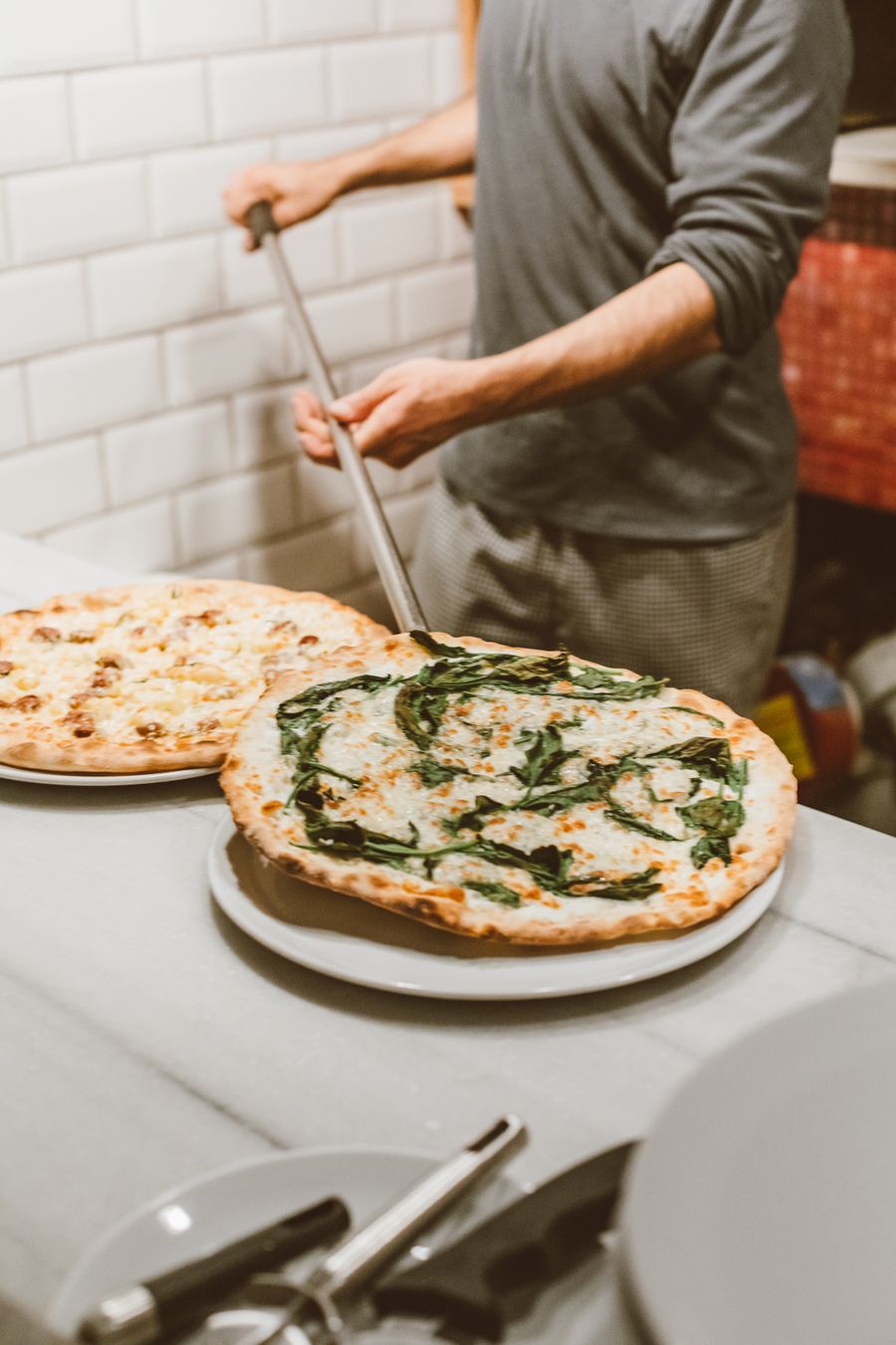 Maestro pizzaiolo sirviendo una pizza recién salida del horno