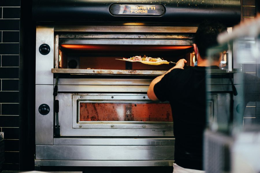 Interior del horno de leña con la pizza entrando