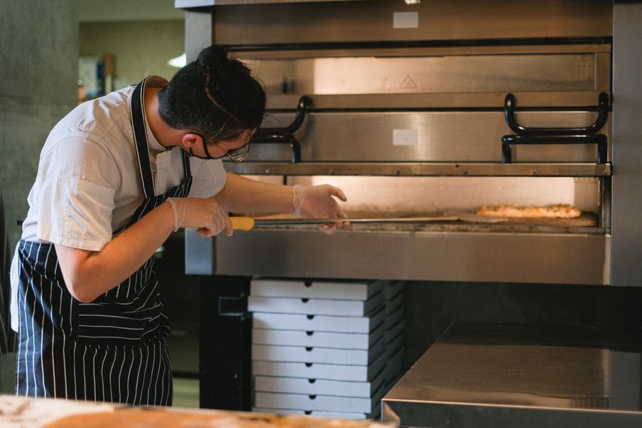 Pizzaiolo introduciendo una pizza en el horno con pala